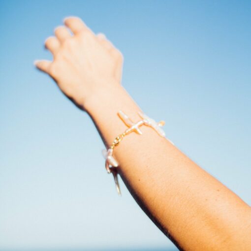 Joya artesanal con perlas naturaesl cruzadas y cierre dorado, diseño femenino inspirado en el mar.
